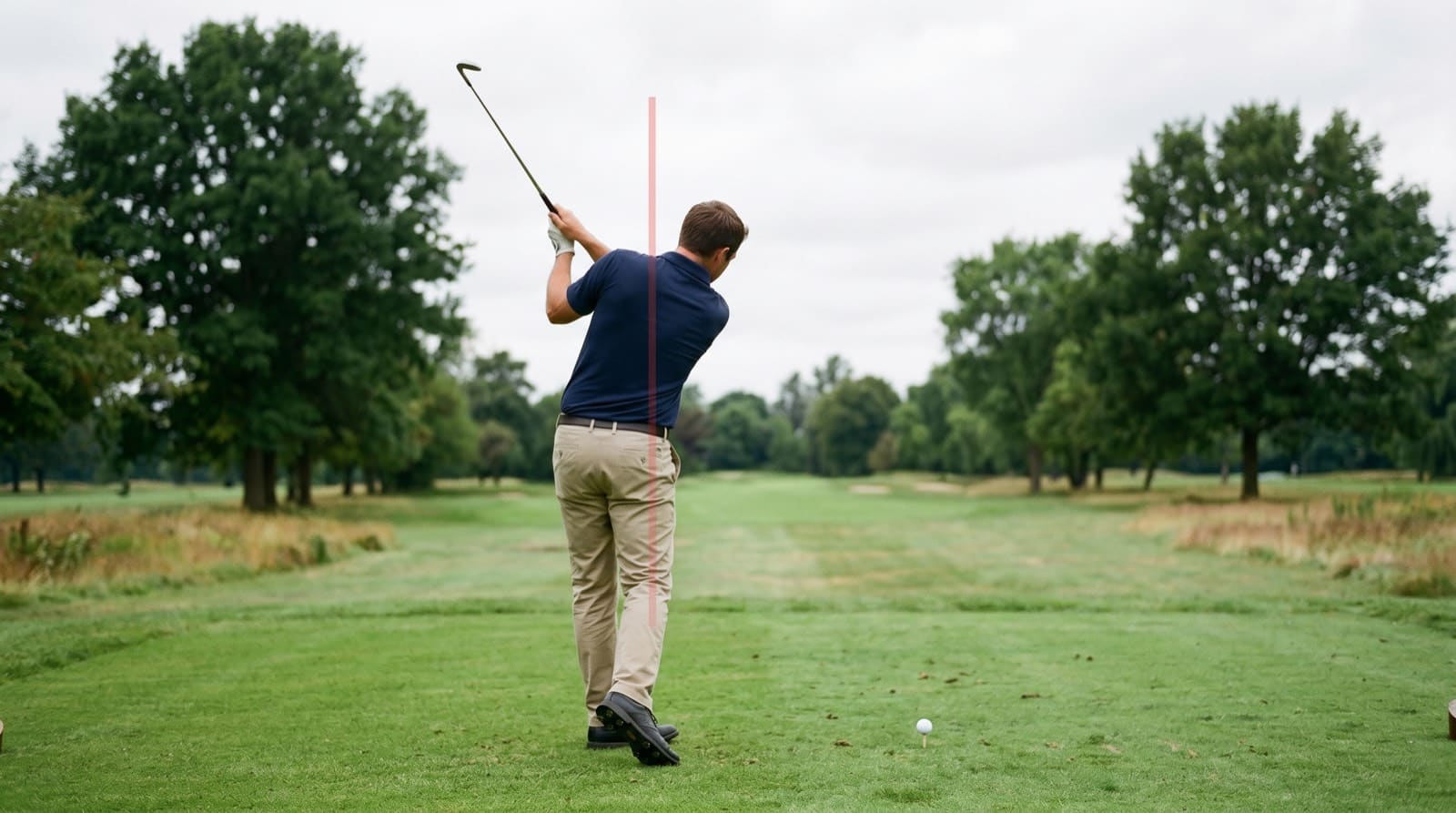 Down-the-line view of a golfer's swing on a fairway with a vertical reference line through the body, used to check posture and early extension.